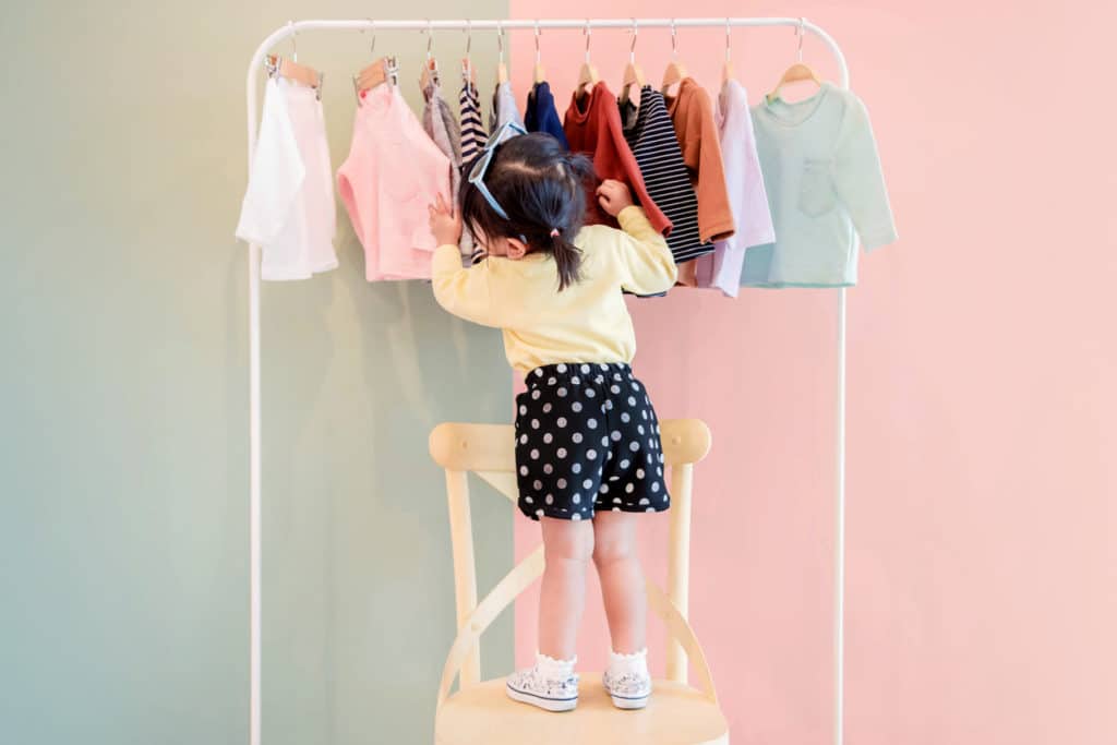 une petite fille choisis des vêtements
