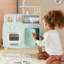 enfant joue avec une cuisinière en bois