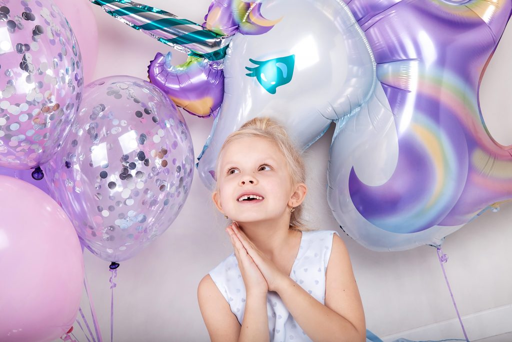 Petite fille blonde entourée de ballon paillettes et licorne