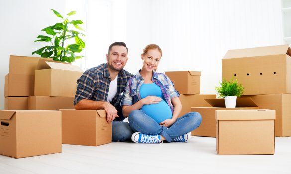 femme enceinte et homme assis à côté de cartons de déménagement