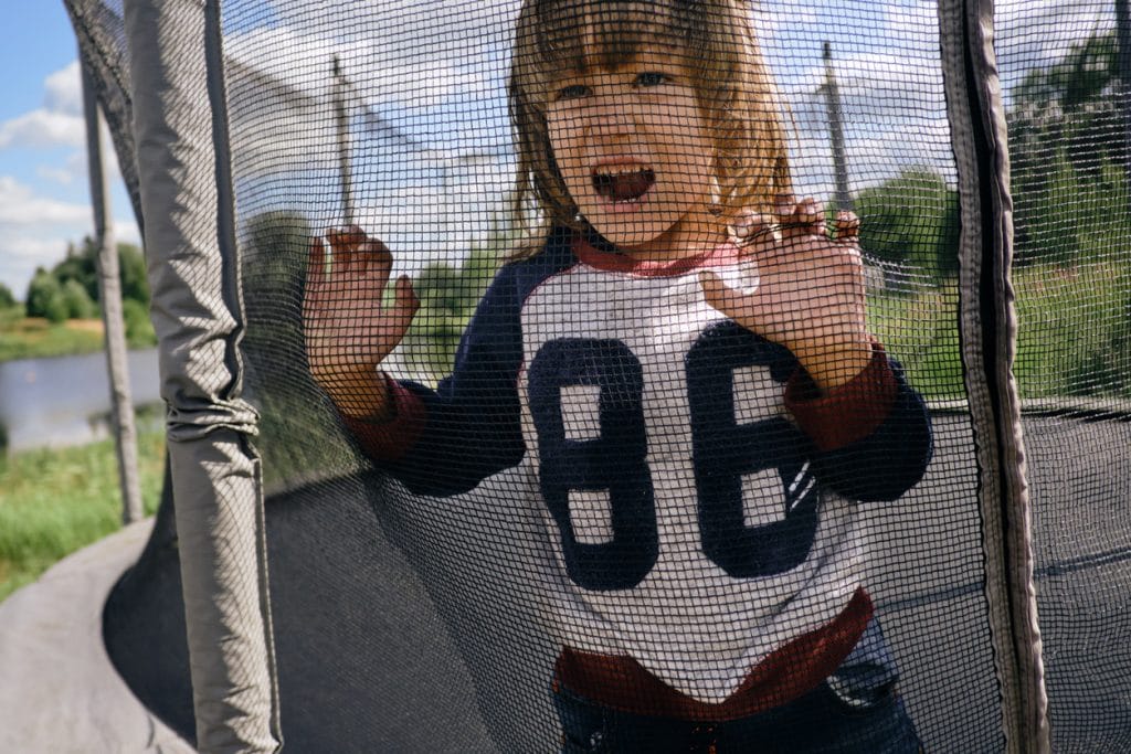 enfant derrière un filet de trampoline