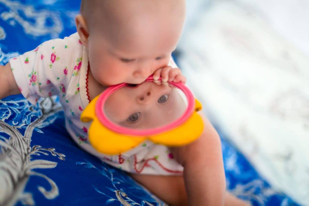 bébé allongé sur un tapis se regarde dans un miroir