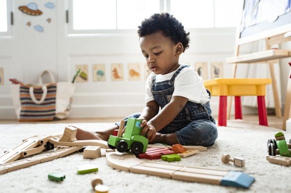 petit garçon assis joue avec des jeux en bois