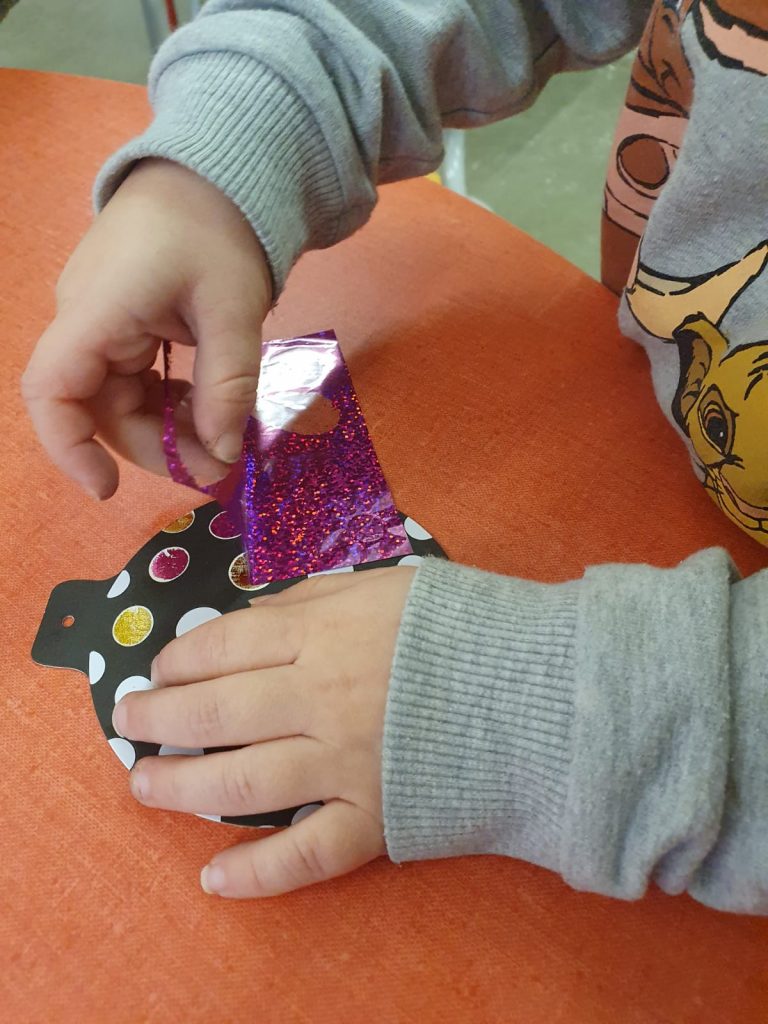 enfant decore une boule avec du papier métallisé