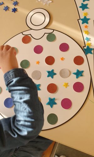 enfant en maternelle décore une boule de noel