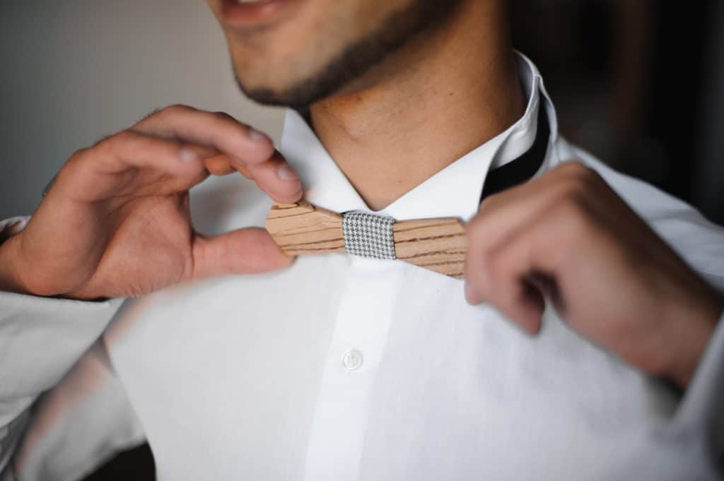 mains d'un homme tiennent ur un noeud papillon en bois