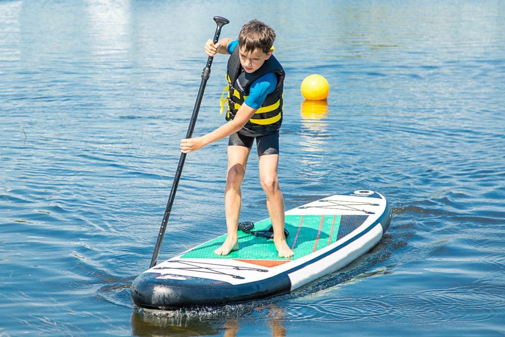 Jeune garçon debout rame sur un paddle