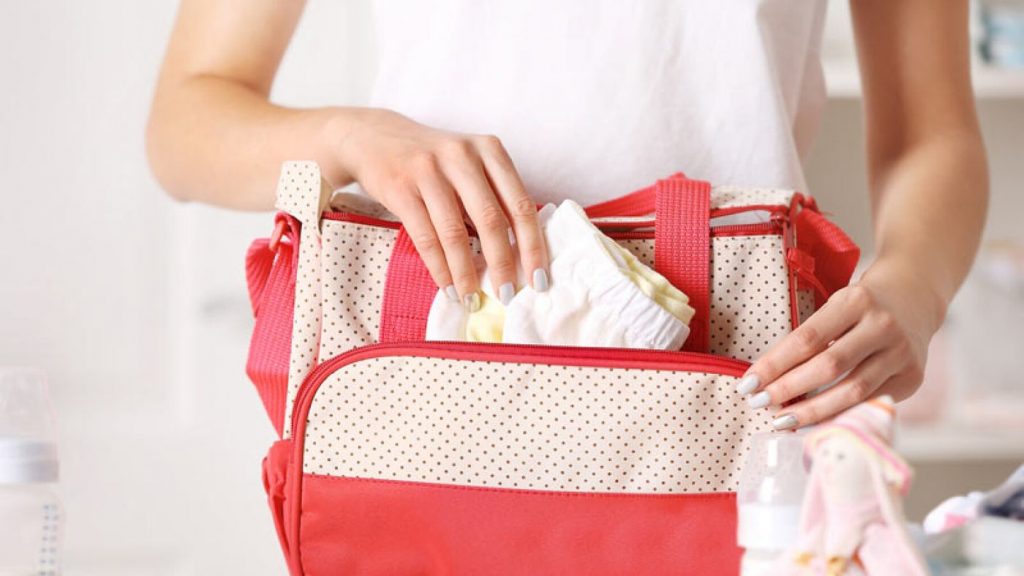 femme range des couches dans un sac à langer