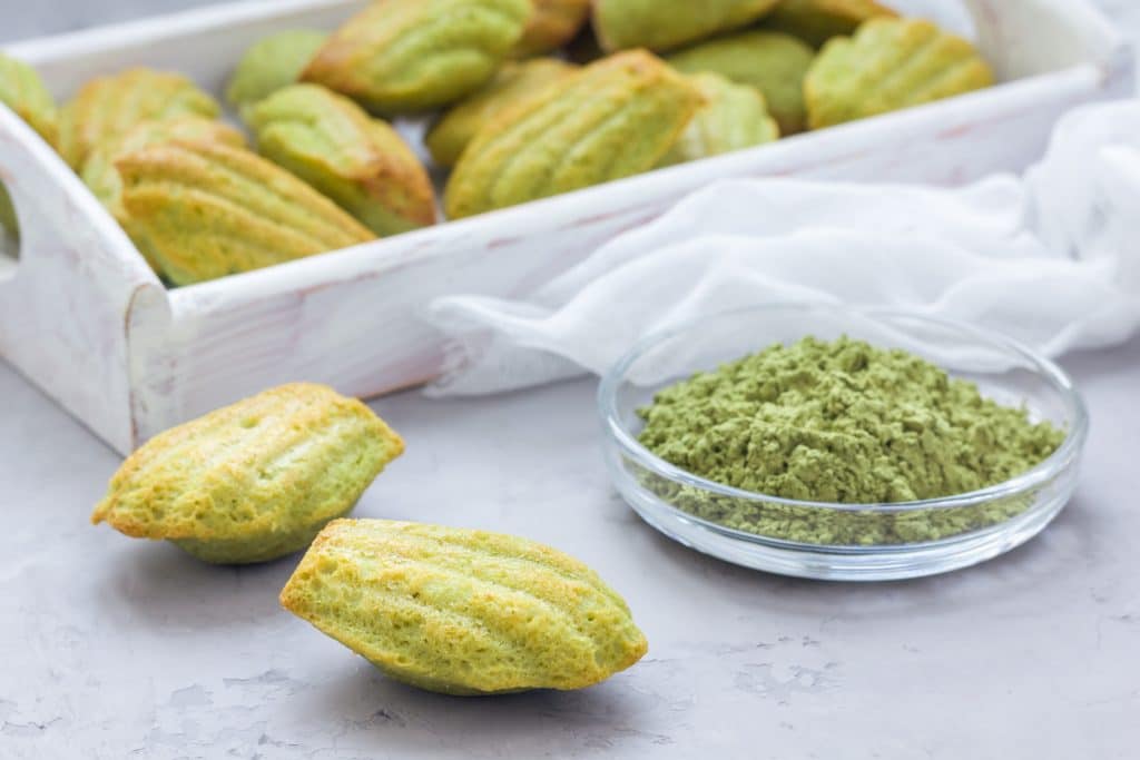 madeleines au thé vert posé sur une table à côté de thé en poudre