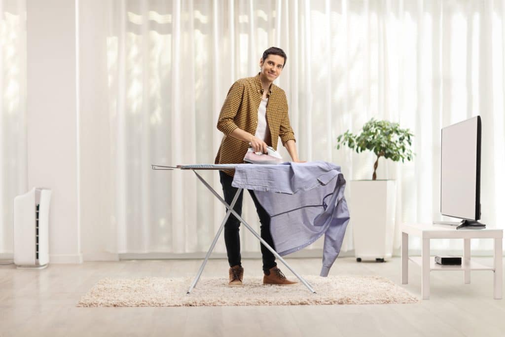 homme debout devant une planche à repasser