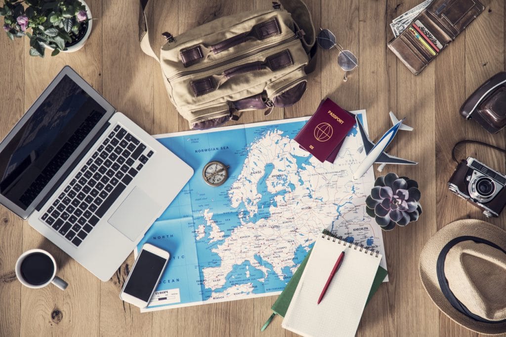carte du monde et passeport posé sur une table à côté d'un ordinateur