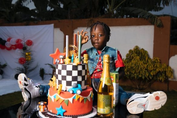 photo d'un enfant assis devant un gâteau d'anniversaire voiture de course