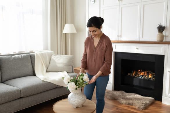 jeune femme pose decore son salon avec un vase et des fleurs