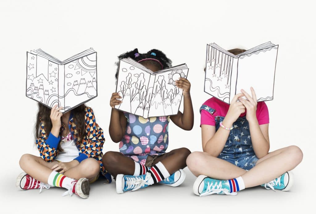 3 enfants assis lisent une bd