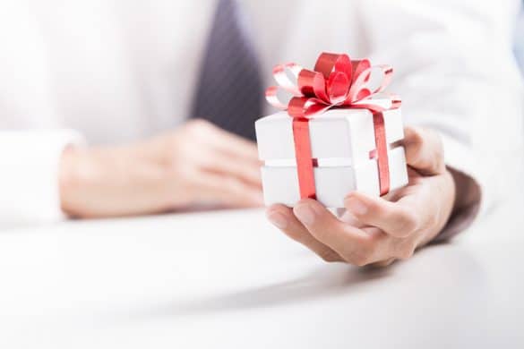 homme tend à cadeau boîte carrée avec ruban rouge