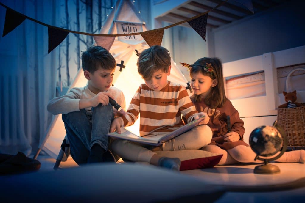 3 enfants 2 garçons et une fille lisent un livre