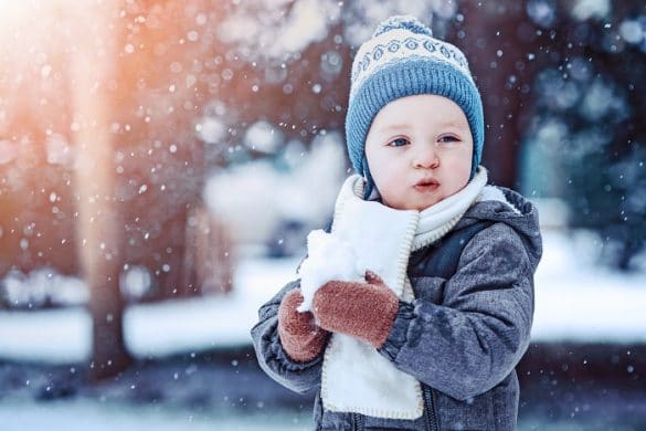 enfant porte un bonnet et une écharpe et un manteau joue dans la neige froid