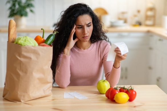 femme se tient la tête en regardant le prix de ses courses