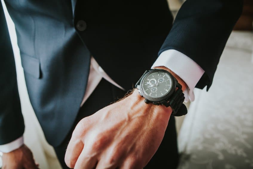 homme en costume porte une montre au poignet