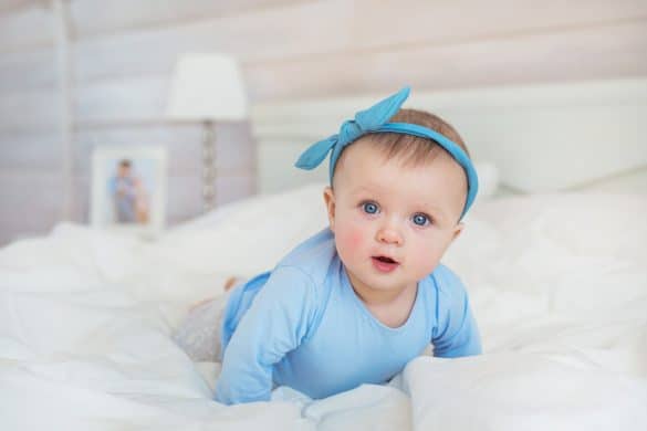 petite fille aux yeux bleus allongée sur un lit avec robe bleu et bandeau