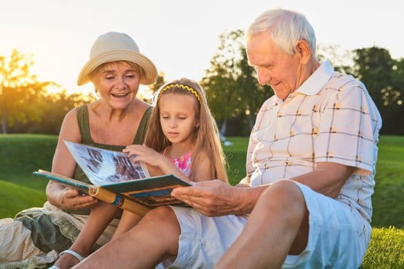 grands parents regardent un album photo avec une jeune fille