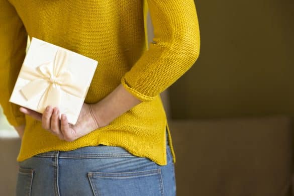 femme tient un cadeau caché dans son dos