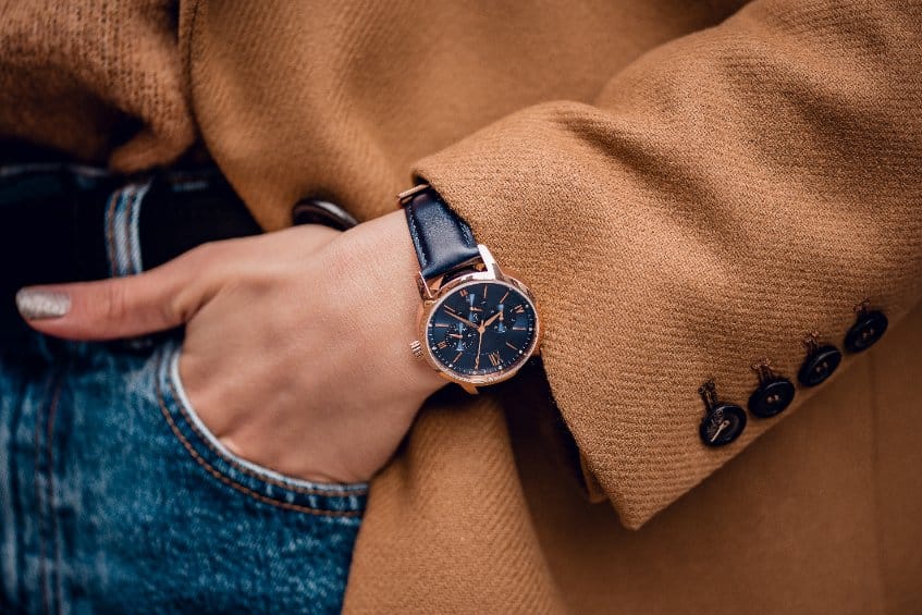 femme avec un manteau camel porte une montre de luxe