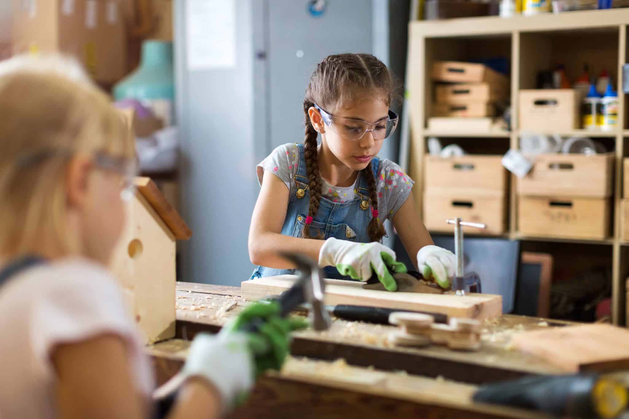 petite fille fait du bricolage avec du bois et des outils