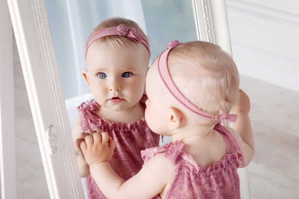 petite fille yeux bleus porte une robe et un bandeau rose