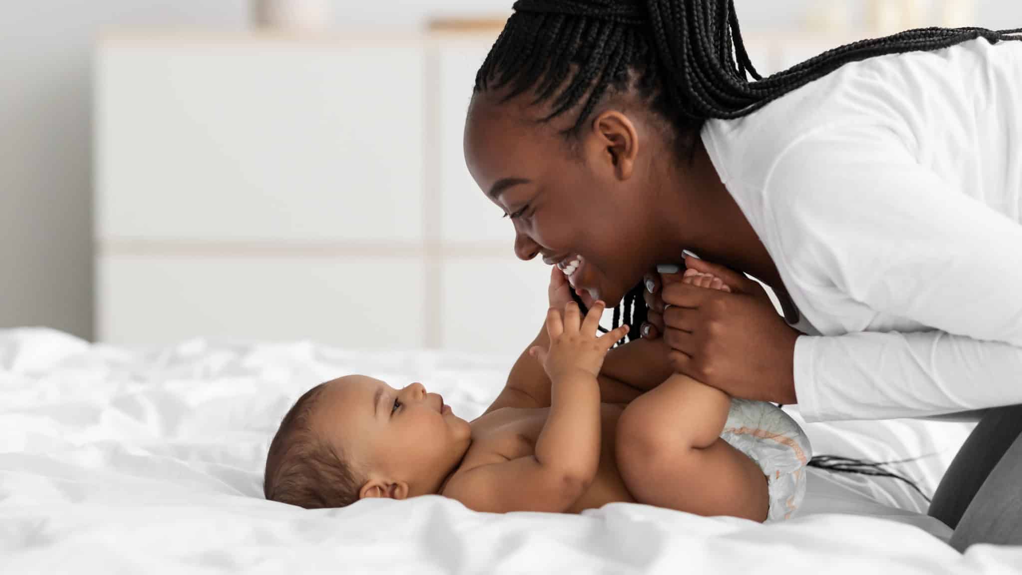 maman penchée sur son bébé et fait des sourires 