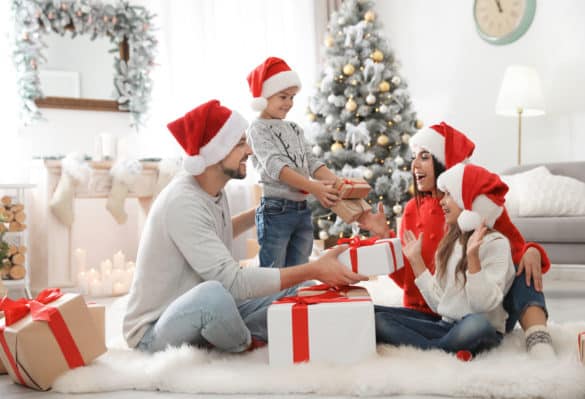 famille qui échange un cadeau avec bonnet de noel rouge sur la tête