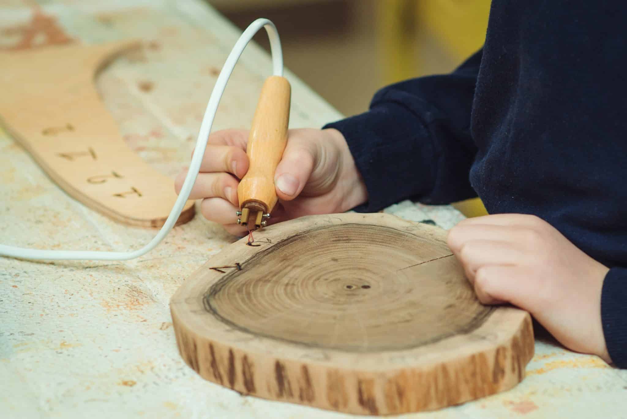 personne qui utilise un pyrograveur sur une planche ronde en bois