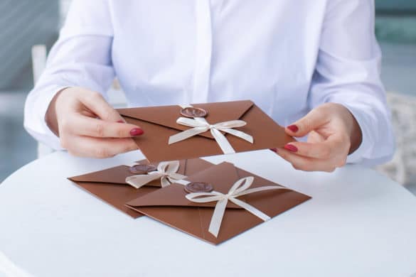 femme tient dans sa main une enveloppe avec un ruban blanc