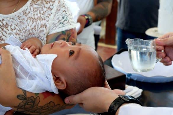 bébé dans les bras d'une femme pour un baptême