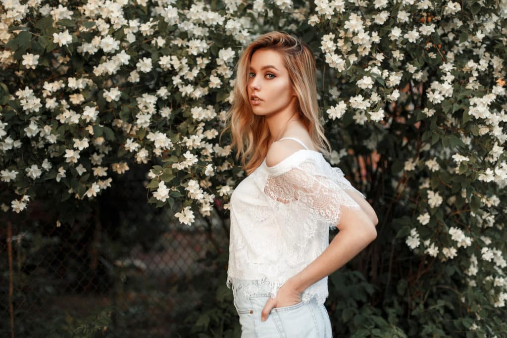 jeune femme blonde porte un haut en dentelle blanche