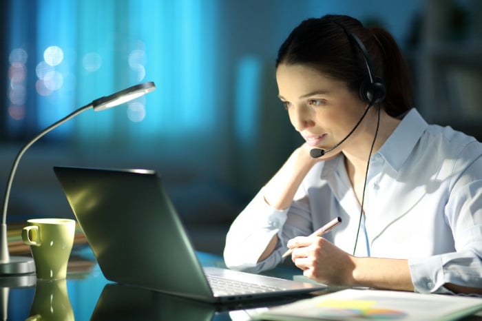 Jeune femme avec un casque sur la tête assise devant un ordinateur portable