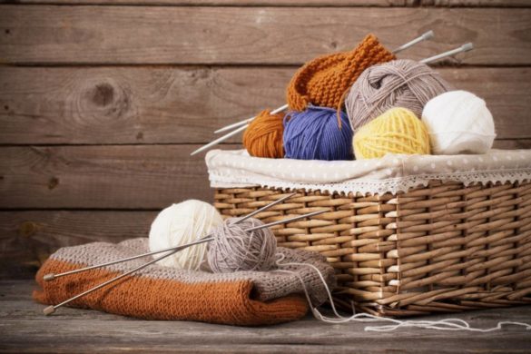 Pelotes de laine de couleurs avec aiguilles dans un panier en osier